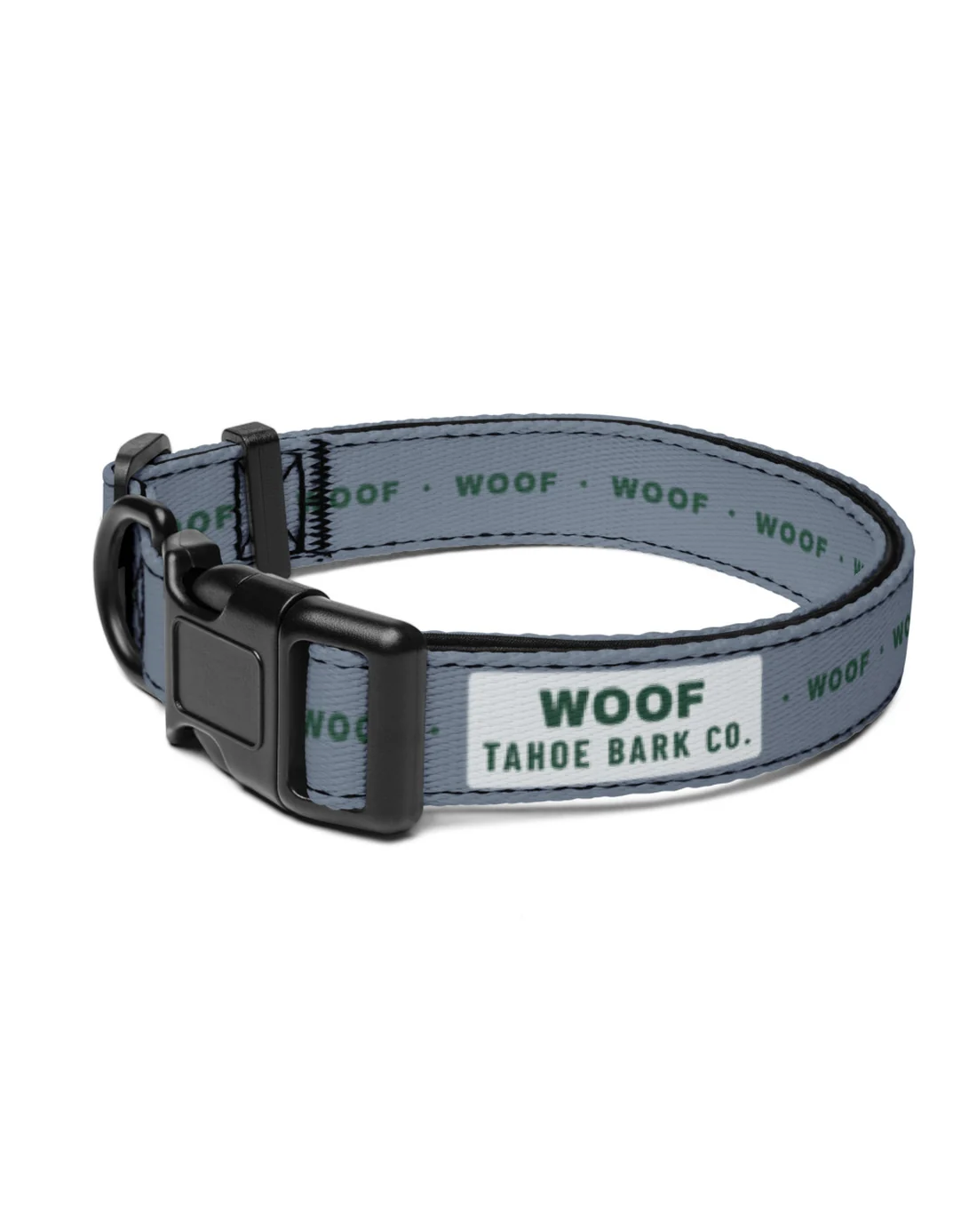 The Woof collar laid flat: the silver WOOF / TAHOE BARK CO. label beside the black plastic buckle, WOOF repeating in pine around the granite strap.