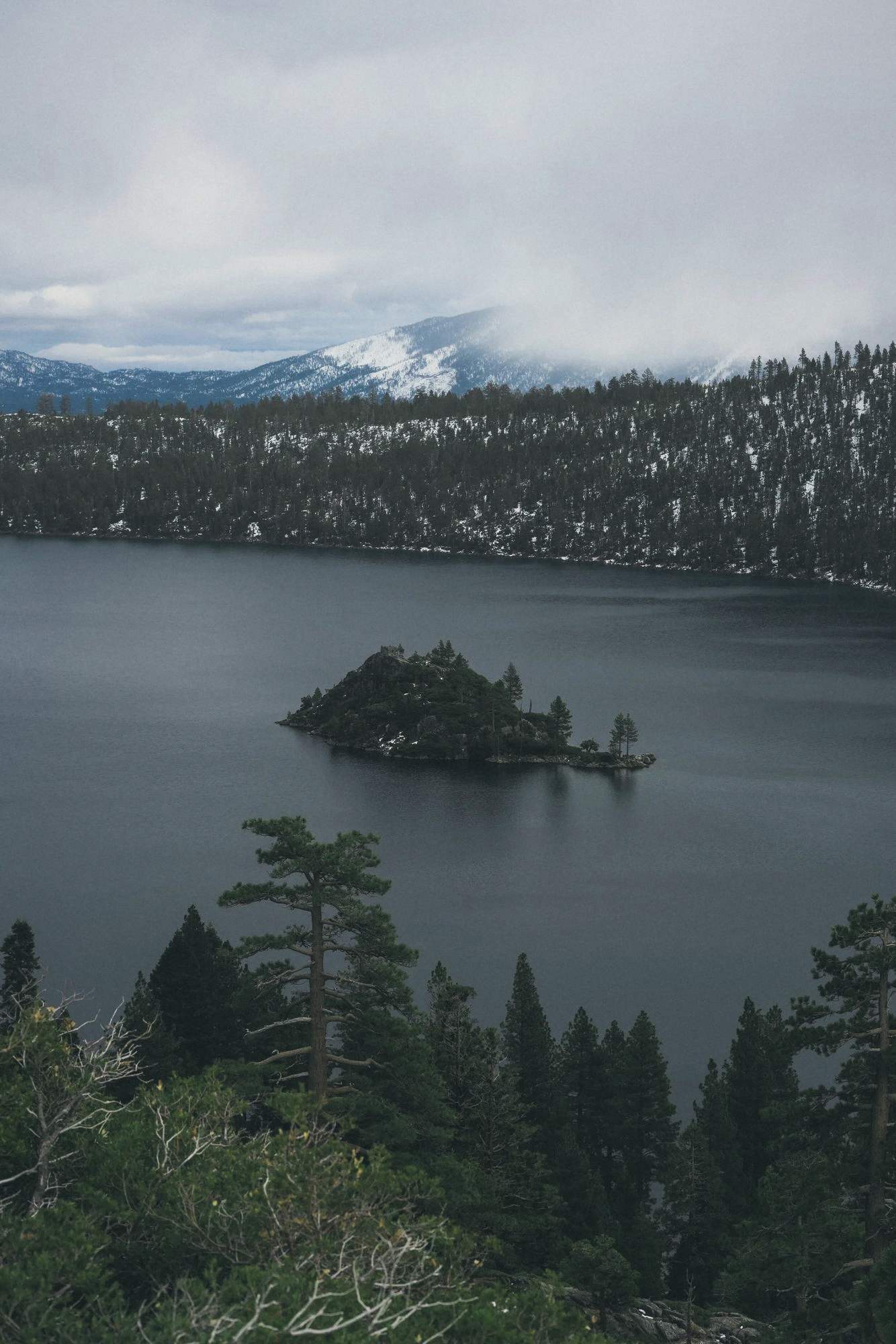 Emerald Bay at Lake Tahoe, ringed by pines under grey light.