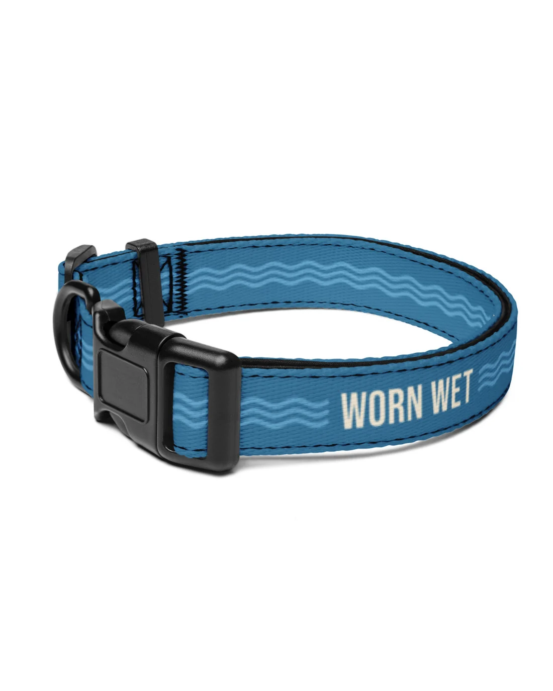 The Worn Wet collar laid flat: WORN WET in cream beside the black plastic buckle, pale blue waves around the Cascade strap.