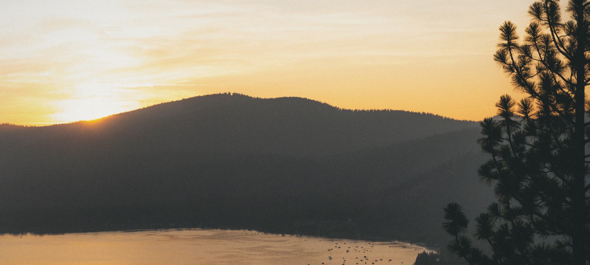 The sun going down behind a forested ridge above Lake Tahoe, seen from a fire lookout.