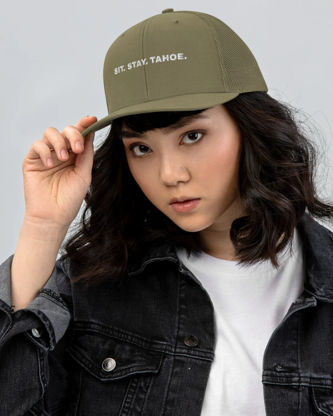 The Sit. Stay. Tahoe. design on a trucker cap, worn by a model.