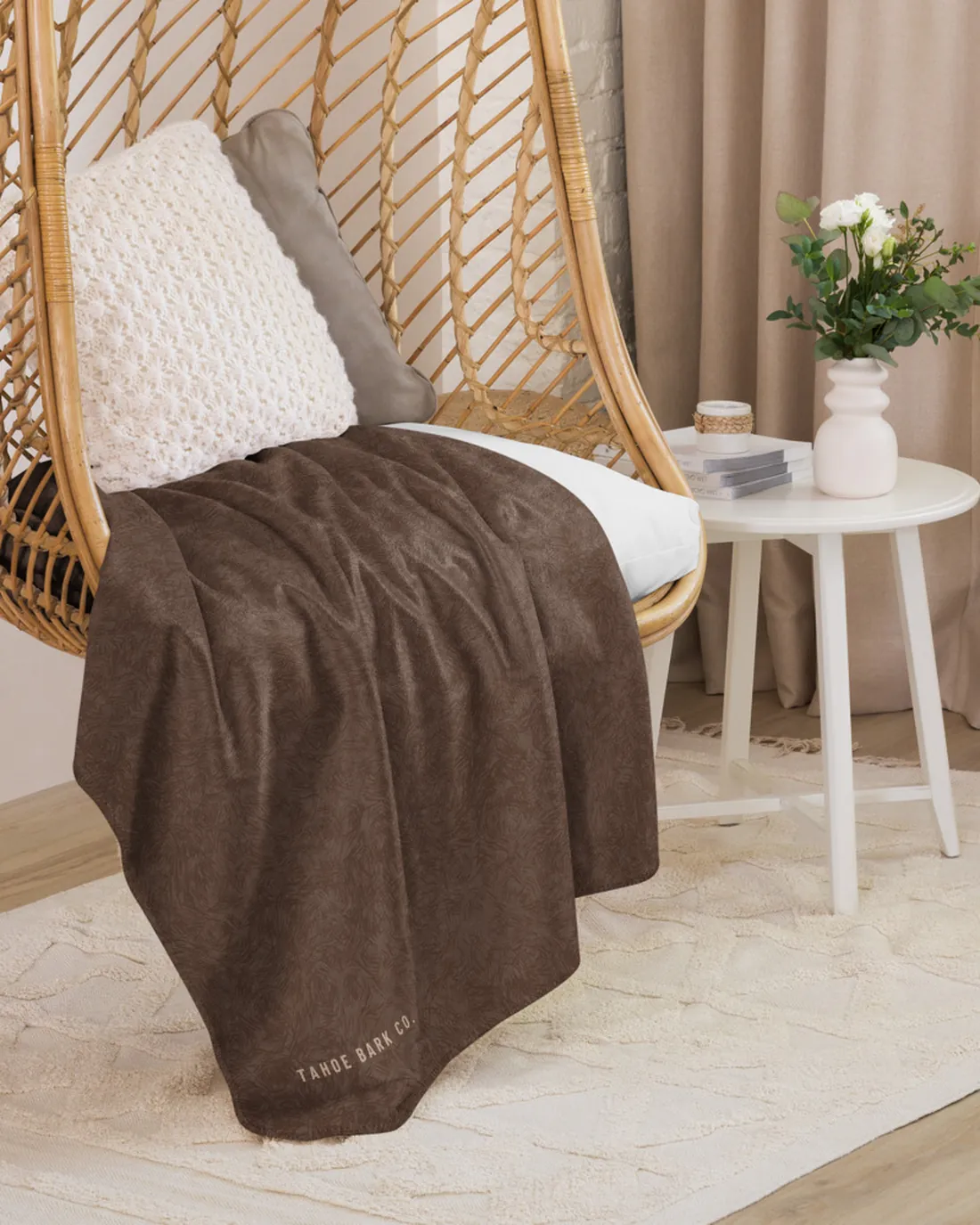 The Coat Match design in Chocolate on a blanket, draped over a hanging chair.